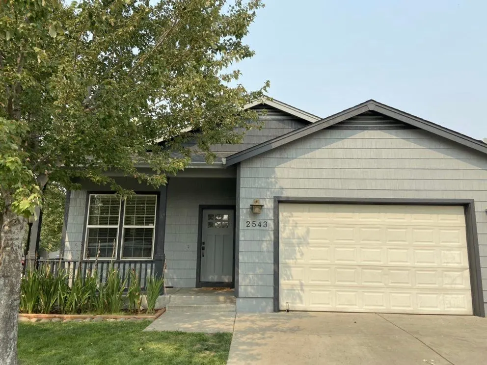 Home with gray-blue siding, a covered front porch, and a two-car garage in the Central Point, Oregon area served by Next Gen Contracting