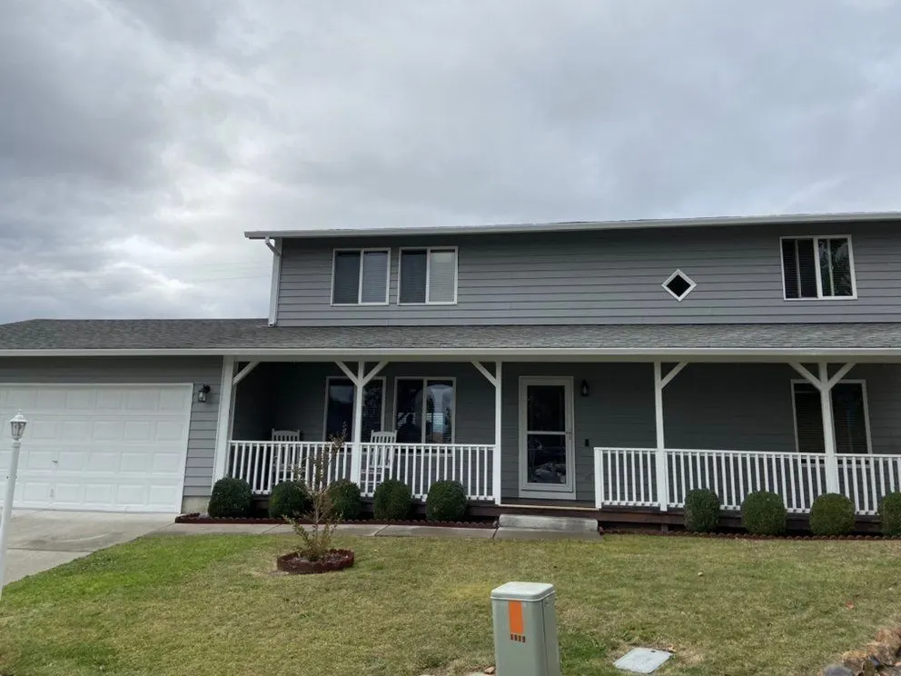 Two-story home with gray lap siding and a full-width covered porch in the Gold Hill, Oregon area served by Next Gen Contracting