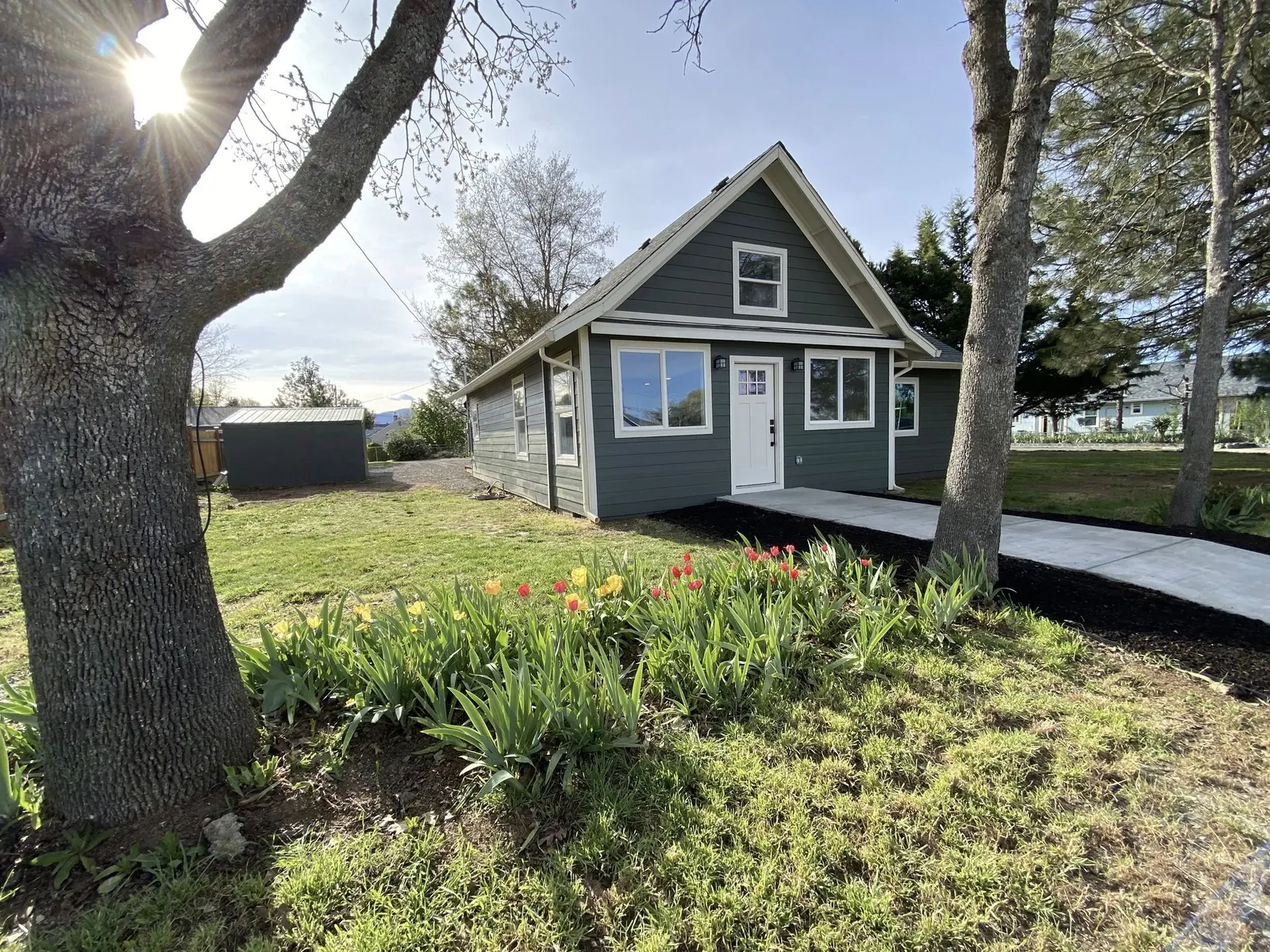 Home with dark gray-blue lap siding and white trim, with a tulip bed out front, in the Phoenix, Oregon area served by Next Gen Contracting