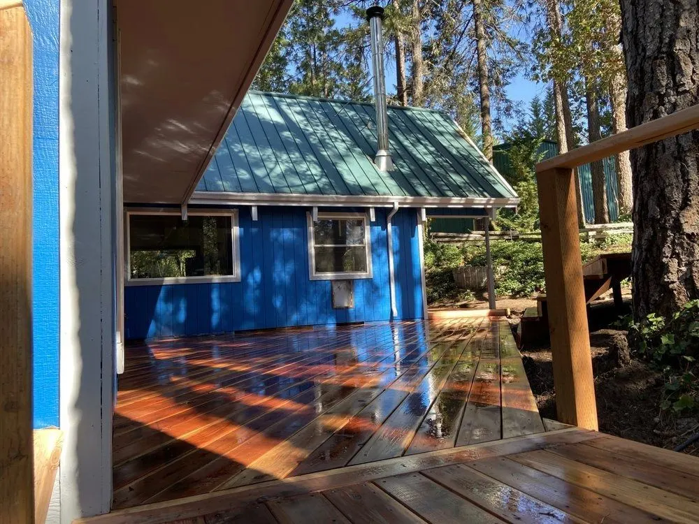 Blue cabin with a green metal roof among the evergreens in the Shady Cove, Oregon area served by Next Gen Contracting