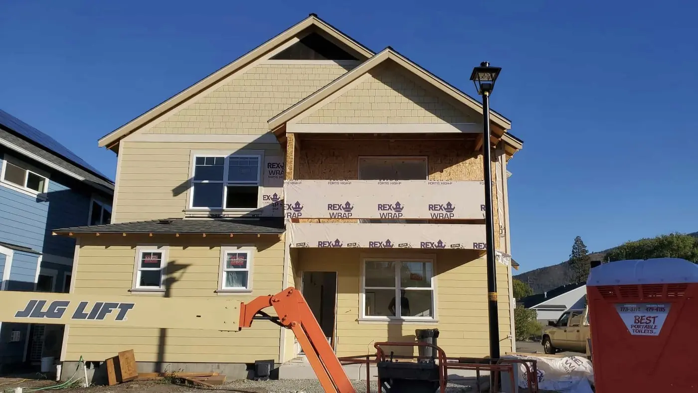 Two-story home mid-siding-installation with a boom lift on the job site, Next Gen Contracting in Southern Oregon