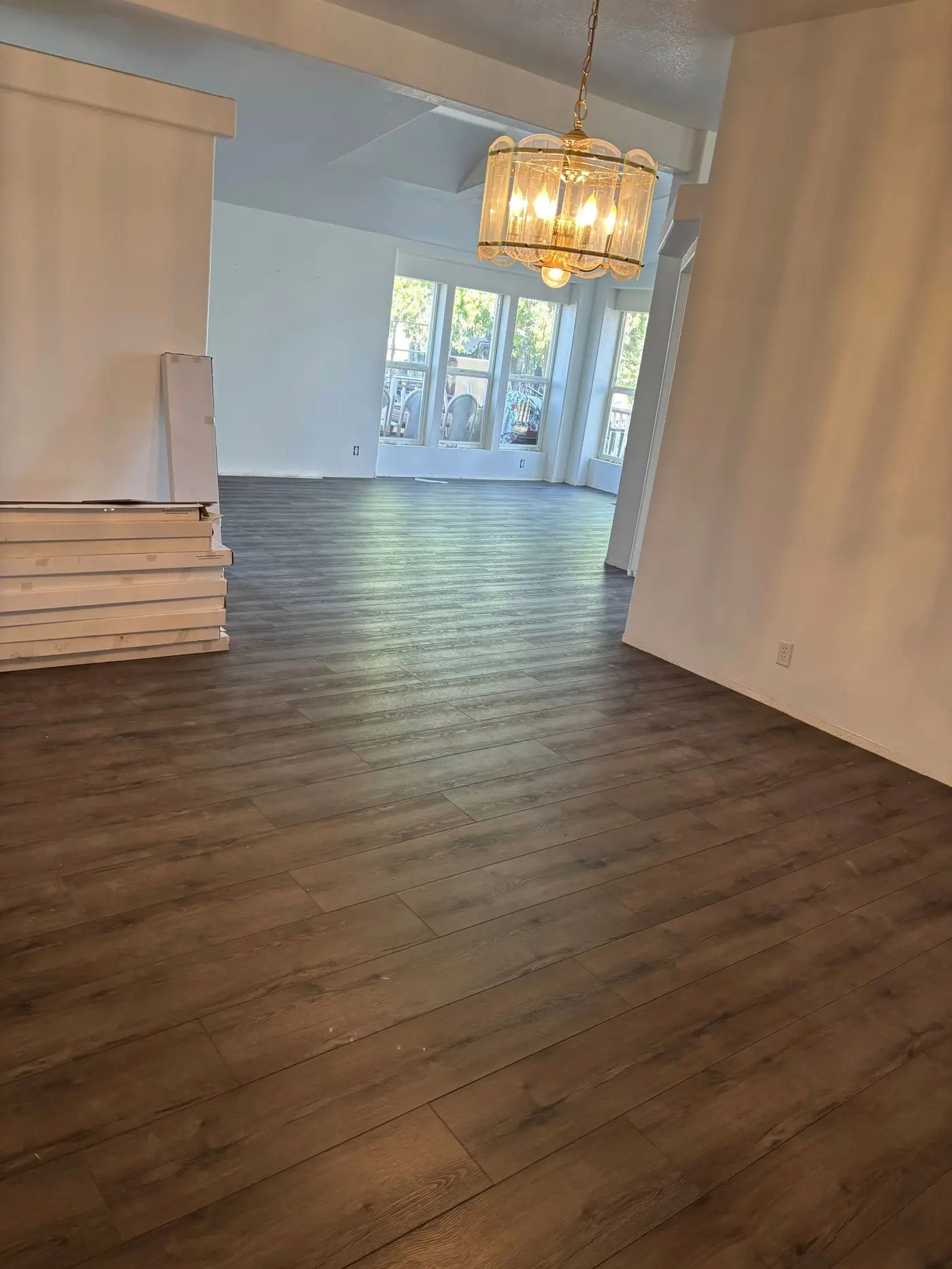 Living room remodel with new dark wood-look flooring and fresh white walls by Next Gen Contracting in Southern Oregon