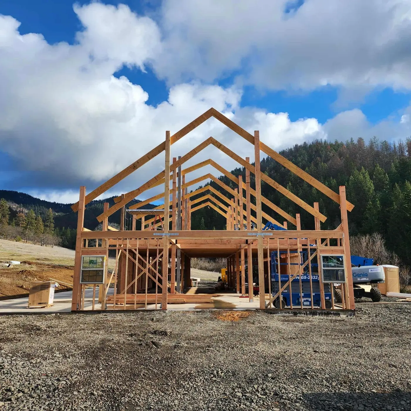 Wood framing going up on a large new build against forested Southern Oregon mountains, Next Gen Contracting